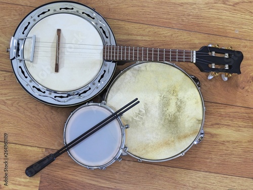 Three Brazilian musical instruments: samba banjo, pandeiro (tambourine) and tamborim with drumstick on a wooden surface. The instruments are widely used to accompany samba, a popular Brazilian rhythm.