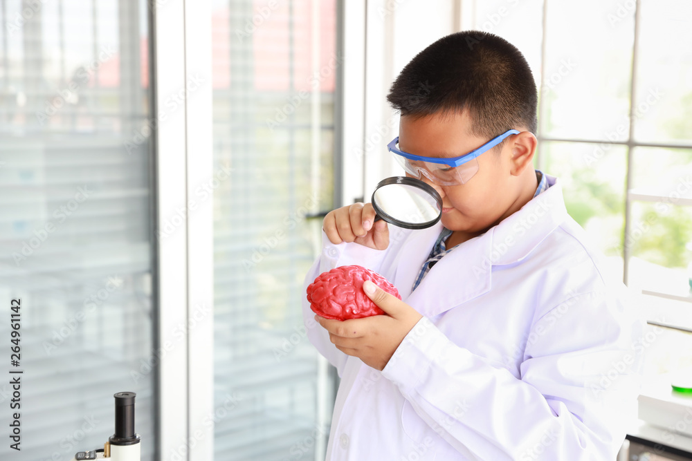happy boys learning how to use magnifying glass and holding brain symbol (education and scientist concept)