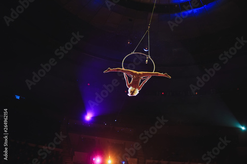 Aerial acrobat in the ring. A young girl performs the acrobatic elements in the air ring.