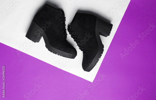 Women's suede boots on purple-white angular creative background. Top view