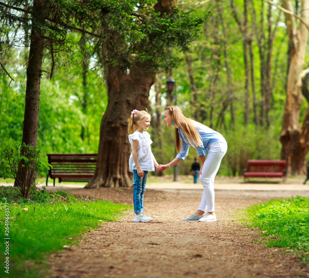 Fototapeta premium Mother with her daughter are walking in city summer park