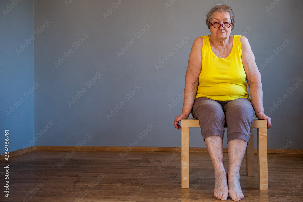 elderly woman with sore legs is sitting on chair and preparing for