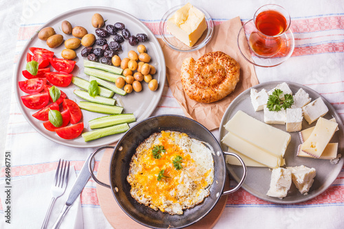 Traditional Turkish breakfast - fried eggs, fresh vegetables, olives, cheese, cake and tea