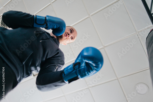 Man in boxing gloves boxing with a punching bag in the gym. Bottom view
