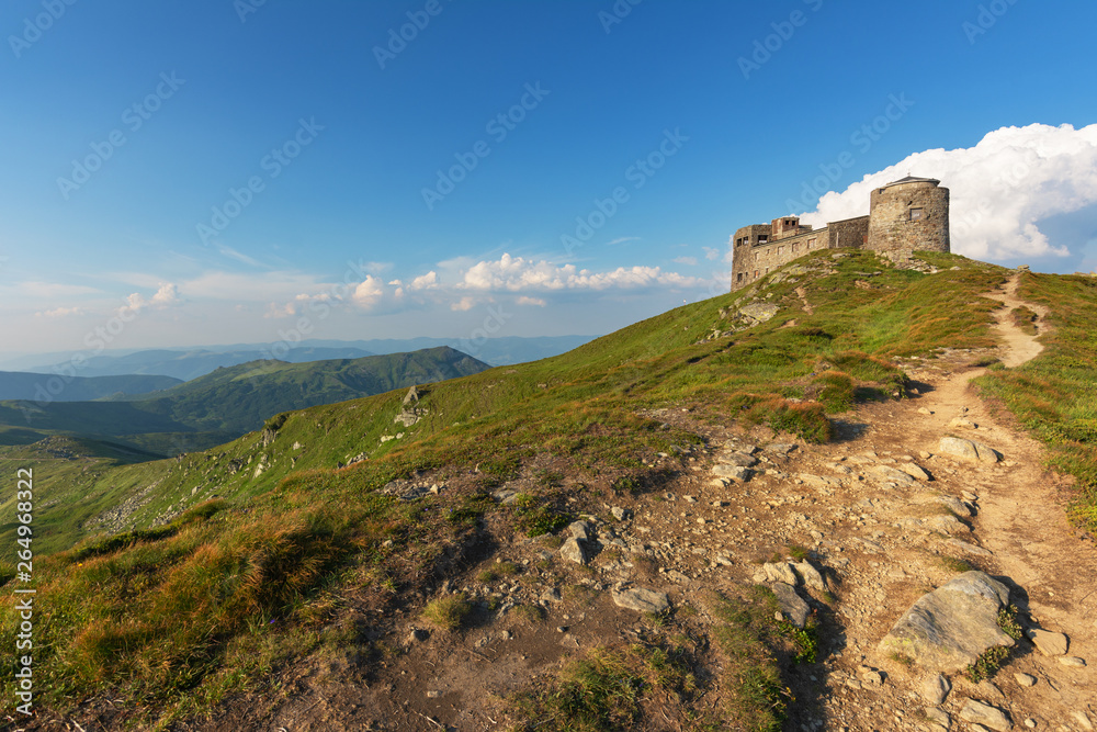 Warm summer season in the Ukrainian Carpathians with view of the observatory White elephant and tourist with a tent against the background of the mountains