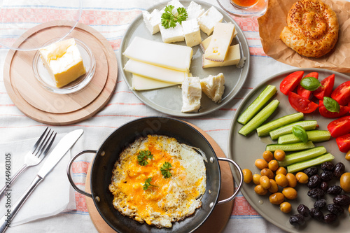 Traditional Turkish breakfast - fried eggs, fresh vegetables, olives, cheese, cake and tea