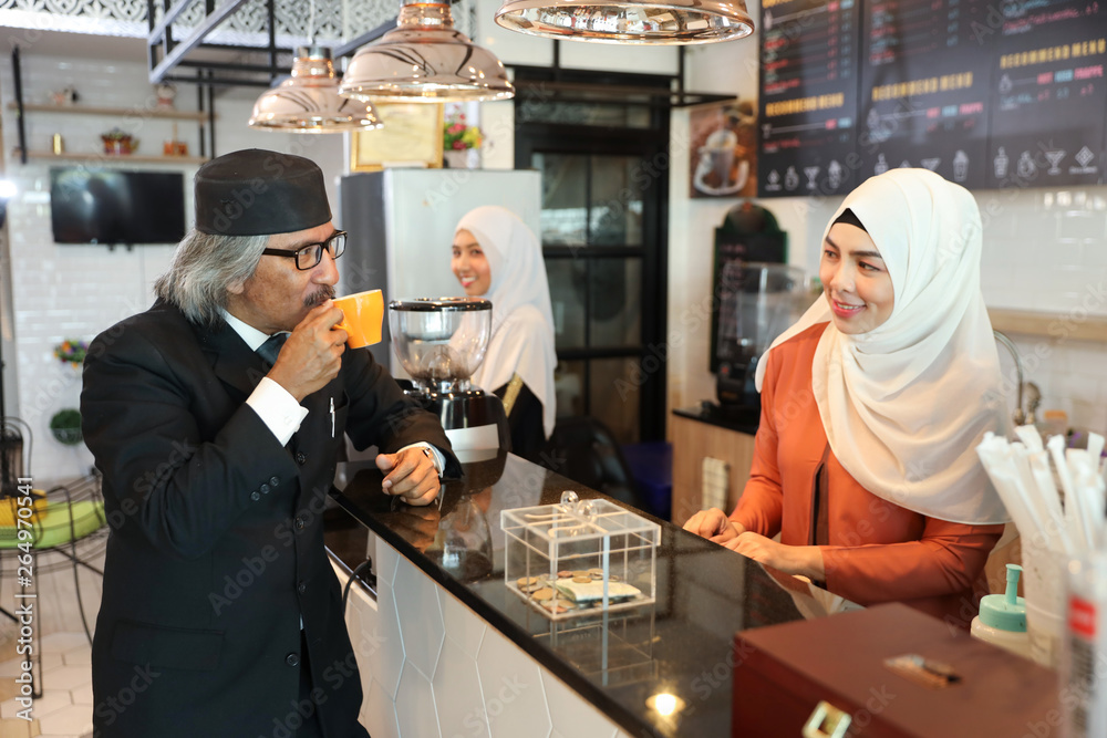 muslim customer businessman wearing black suit drinking coffee at counter with young muslim barista girls background muslim customer businessman wearing black suit drinking coffee at counter with young muslim barista girls background