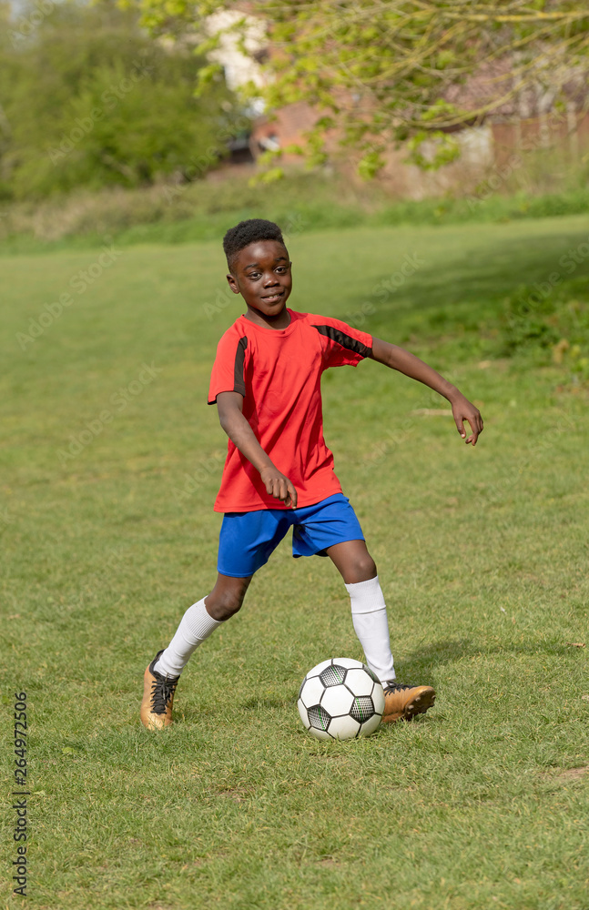 Hampshire, England, UK. April 2019. A nine year old footballer dribbles the soccer ball during a training session in a public park. Hampshire, England, UK. April 2019. A nine year old footballer dribbles the soccer ball during a training session in a public park.