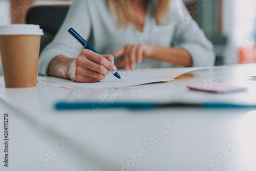 Hand of woman holding blue pen and writing