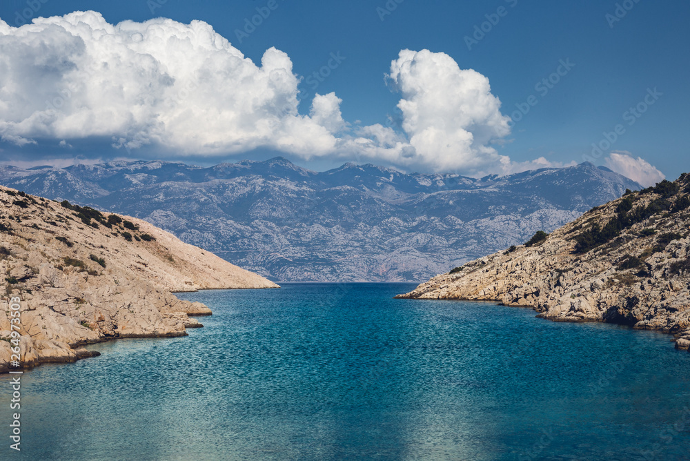 Mediterranean seascape in summer at sunny day with mountains and clouds on background - Croatia (Pag island). Wide view of beautiful bay with hills and crystal blue sea water.