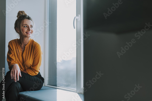 Woman looking away while sitting on the window sill