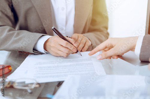 Businesswoman signing contract papers. Group of business people at meeting or negotiation, close-up