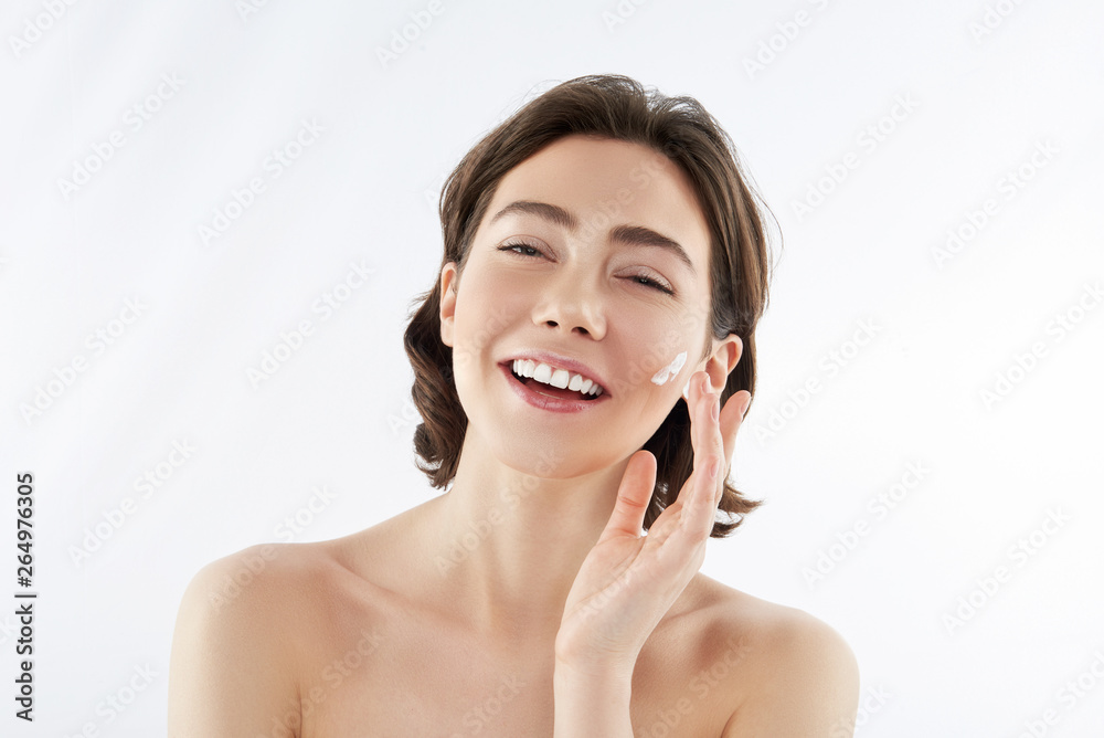 Happy pretty woman applying cream on face Happy pretty woman applying cream on face