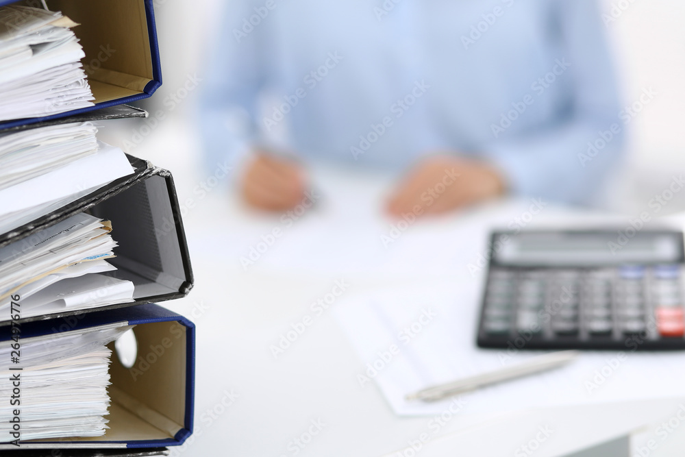 Calculator and binders with papers are waiting to be processed by business woman or bookkeeper back in blur. Internal Audit and tax concept Calculator and binders with papers are waiting to be processed by business woman or bookkeeper back in blur. Internal Audit and tax concept