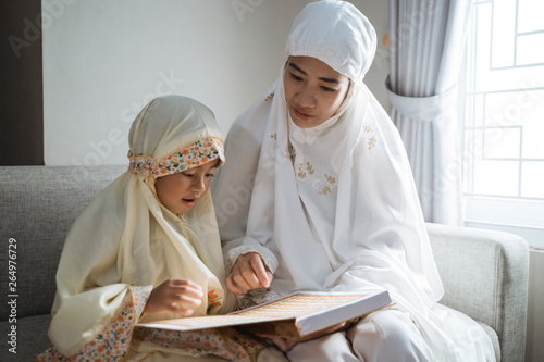 mother and kid reading quran together at home photo