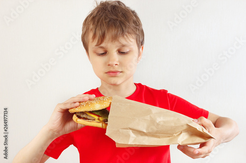 Little cut boy take out a big hamburger from a package on a white background photo