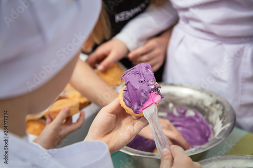 Children preparing topping for cakes