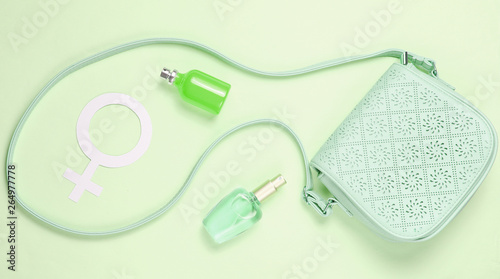 Leather bag, gender symbol of women, perfume bottles on pastel green background. Duotone effect. Top view