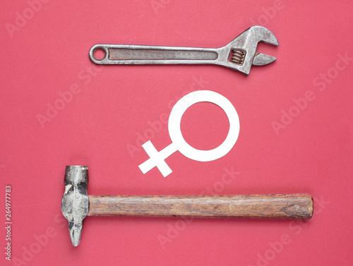 Women choose male work. Feminism. Gender equality. Hammer, wrench, symbol of feminist on red background. Top view photo