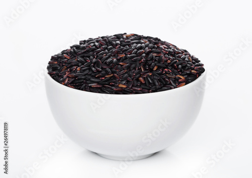 White bowl of raw organic black venus rice on white background. Healthy food.