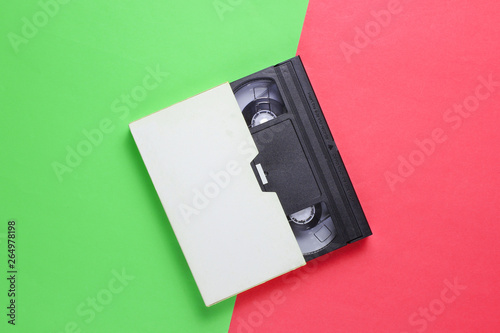 Retro audio cassette in case on pink-green neon background. Top view. Minimalism