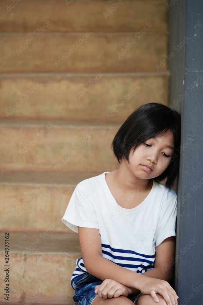 An Asian girl sat unhappy leaning against the wall. An Asian girl sat unhappy leaning against the wall.
