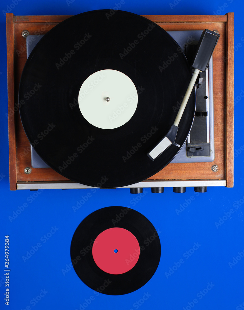 Obraz premium Retro vinyl record player, lp record on blue background. Top view. Retro style. Flat lay.