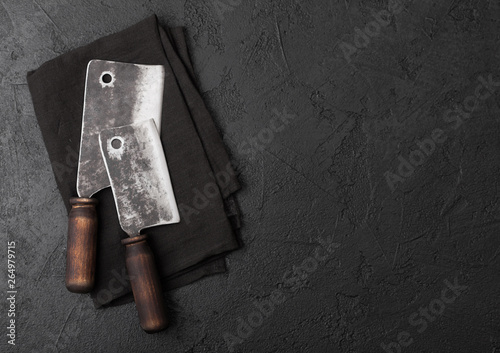 Vintage meat knife hatchets on black stone table background. Butcher utensils. Space for your text