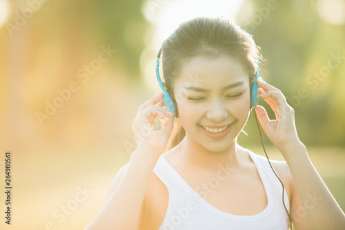 beautiful asian woman listening music in the park