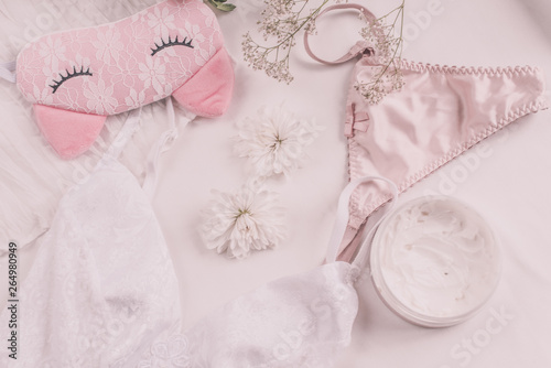 Flat lay for fashion blog and social media. Woman's glamour white and beige beauty accessories on a white background. Lingerie, jewelry, perfumes, cream, soap, panties, sleep mask, spiral hair ties. 