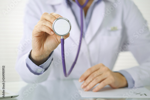 Doctor woman holds stethoscope head, close-up of hands. Physician ready to examine and help patient. Helping and insurance in health care, best treatment and medicine concept