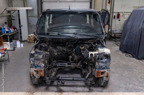 The black car in the body of the van is preparing for painting the body with the help of leveling in the places of damage to the exterior elements with rust without engine in a workshop for repair