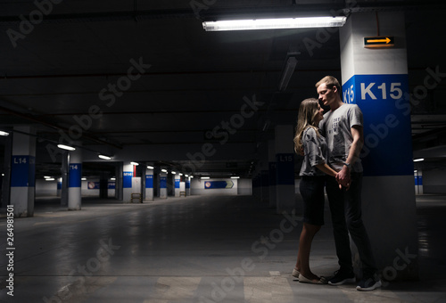 Loving young couple having fun and hugging in underground parking. Parking garage. Family have fun in the parking lot of the supermarket