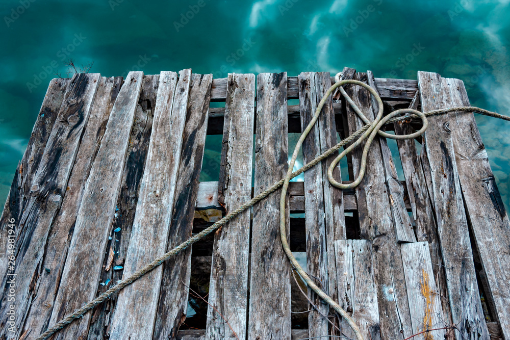 Old wooden pier near the blue sea with nautical ropes and text space.