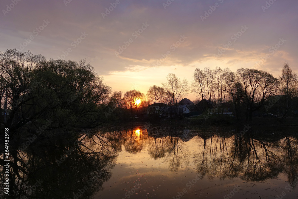 Early morning. Dawn. The sun is reflected in the lake. Rural landscape. Russia.