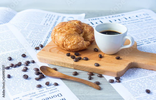 Close Up of Fresh Baked Croissant on wood table with Coffee Mug and  news paper on Relaxing Morning at Home, Bread and coffee, breakfast Healthy food of the city life