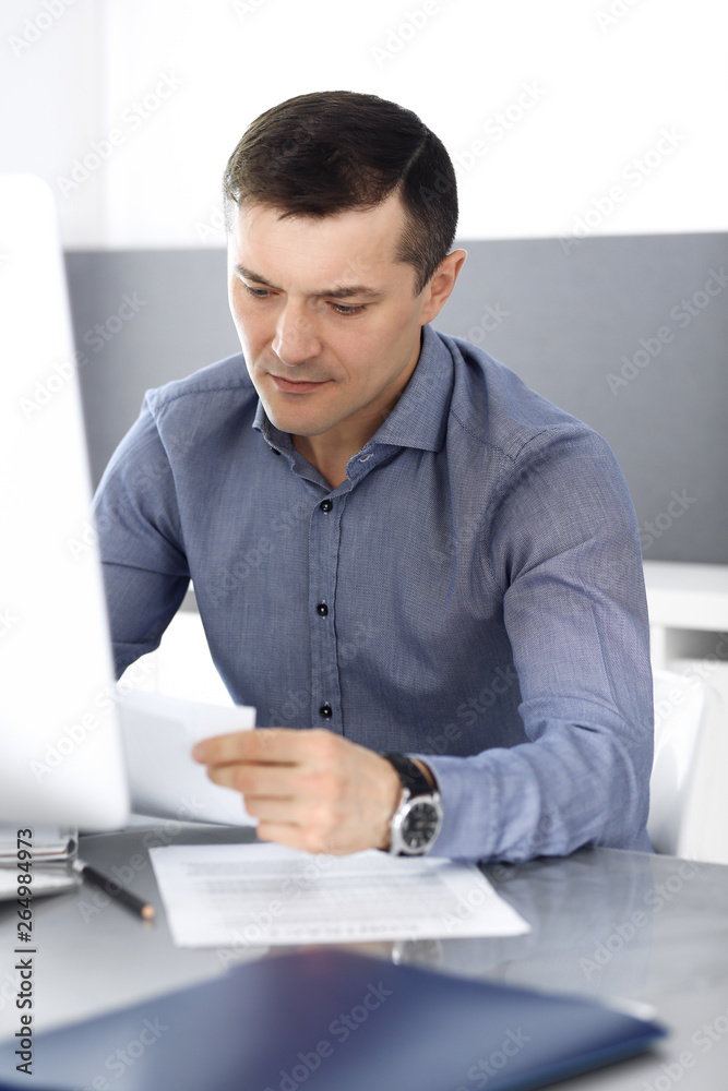 Naklejka premium Businessman working with computer in modern office. Headshot of male entrepreneur or company director at workplace. Business concept