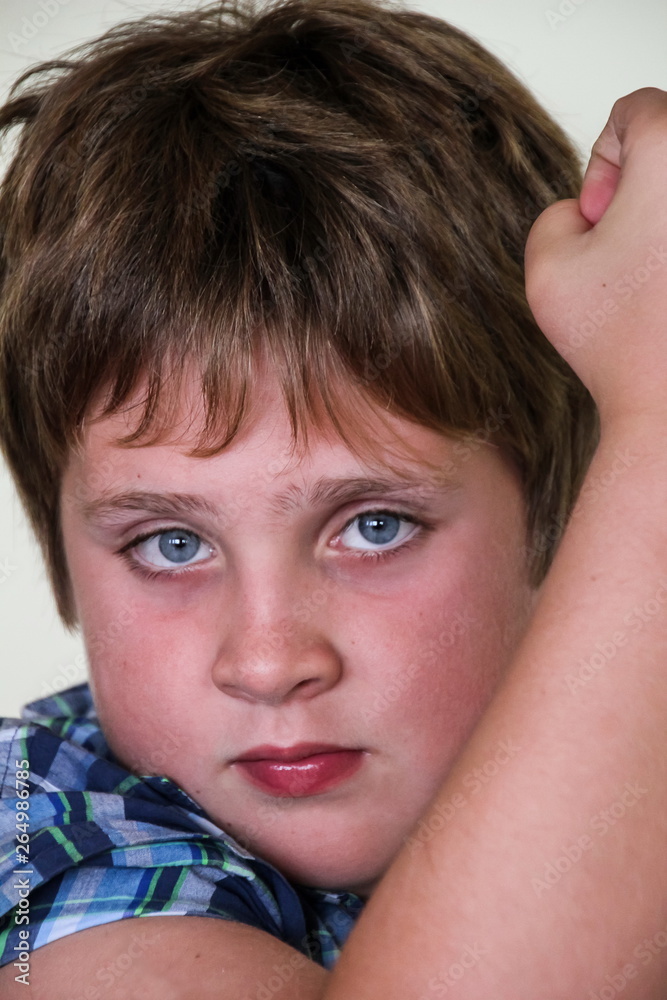 Vertical close up of cute preteen blueeyed angrylooking boy raising