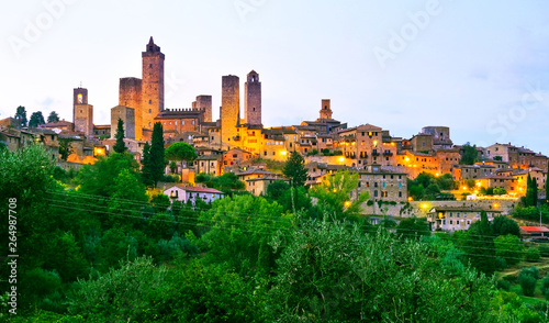 View of the historic cityscape of San Gimignano facing the countryside in Tuscany, Italy at dusk.