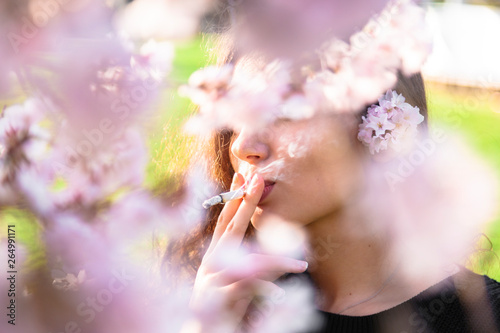 Фотография Girl smokes in park obscured by flower tree branch