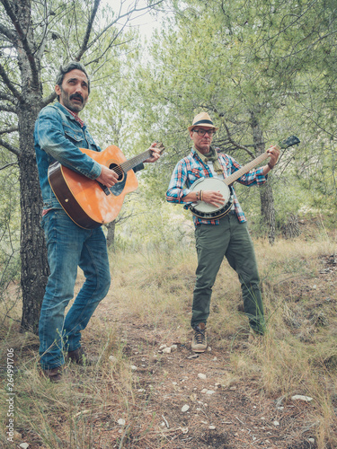 couple of middle-aged men playing the guitar in the field
