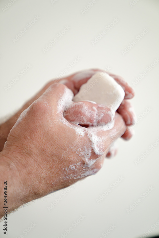 close up of man washing his hands with a bar of soap and soapy suds close up of man washing his hands with a bar of soap and soapy suds