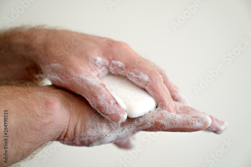 close up of man washing his hands with a bar of soap and soapy suds © makasana photo