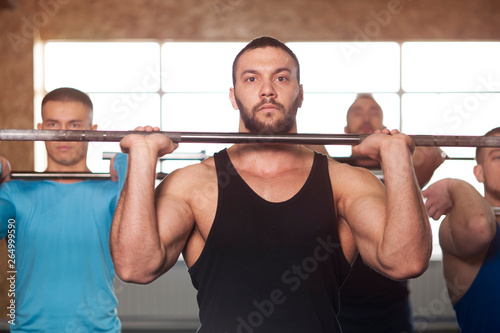 Group of Young Men in Gym Training With Barbells.
