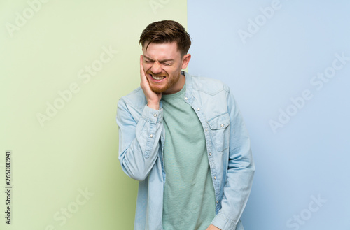 Redhead man over colorful background with toothache