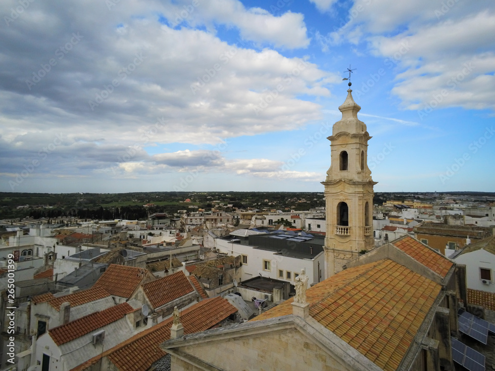 Aerial Shot of the Belltower of the Church of the Nativity in the City of Noci, Near Bari, in the South of Italy, on Partially Cloudy Sky Background