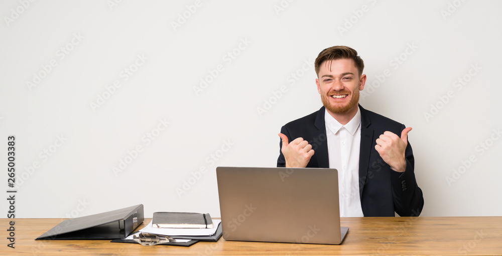 Businessman in a office with thumbs up gesture and smiling Businessman in a office with thumbs up gesture and smiling