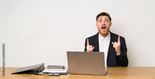 Businessman in a office surprised and pointing up
