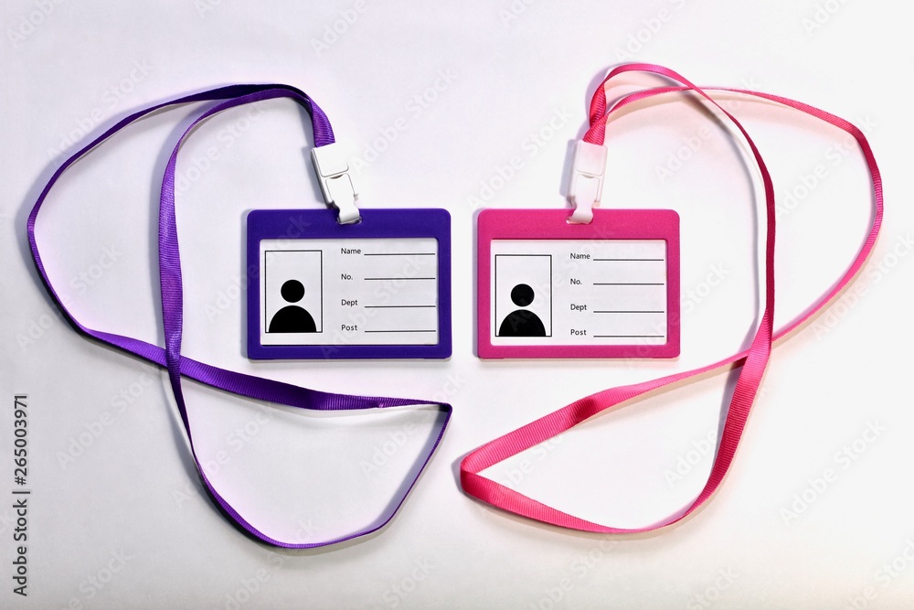 Two blank badges, pink and purple, with satin ribbons for wearing around the neck. On a light background next to each other in the center. Two blank badges, pink and purple, with satin ribbons for wearing around the neck. On a light background next to each other in the center.