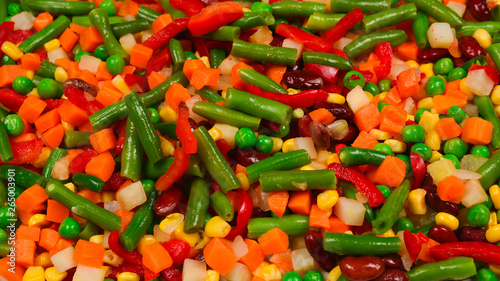 Sliced vegetables, corn, beans, peas, carrots, sweet peppers background.